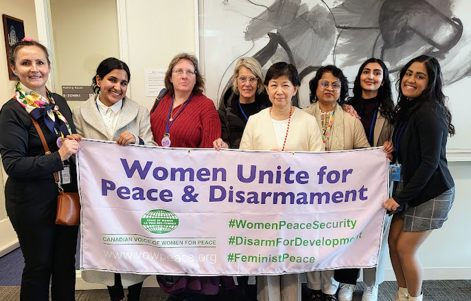 A group of VOW delegates pose with our banner that reads Women Unite for Peace & Disarmament.